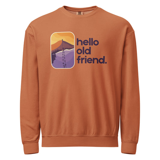 Rust-colored crewneck sweatshirt with retro mountain sunrise graphic, ski lift, and “hello old friend.” text on the front